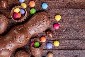 Delicious chocolate easter eggs and sweets on wooden background